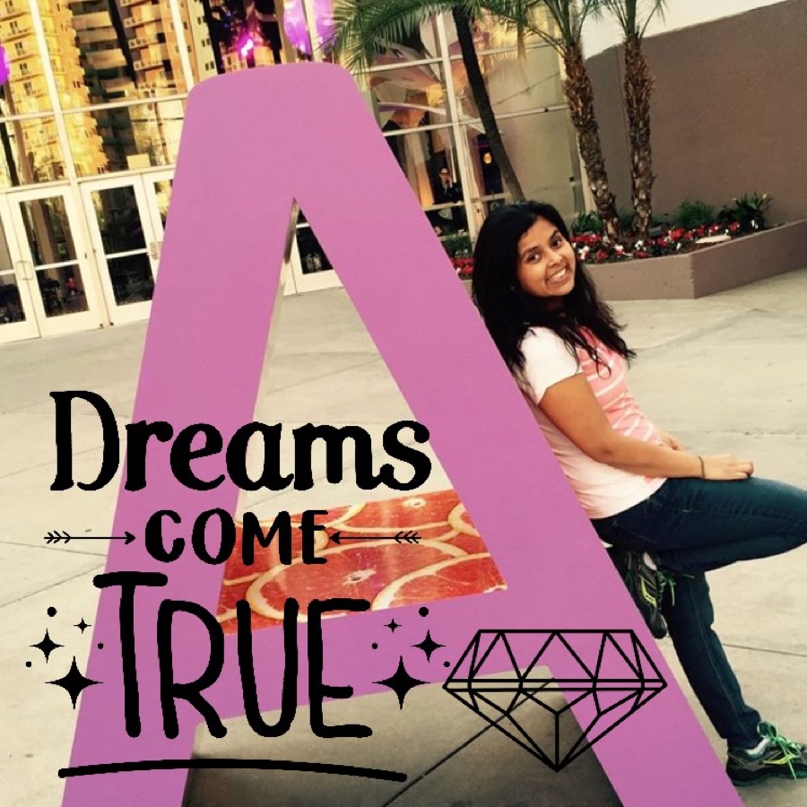 Polished lifestyle image showing a smiling woman beside a large lavender letter installation.