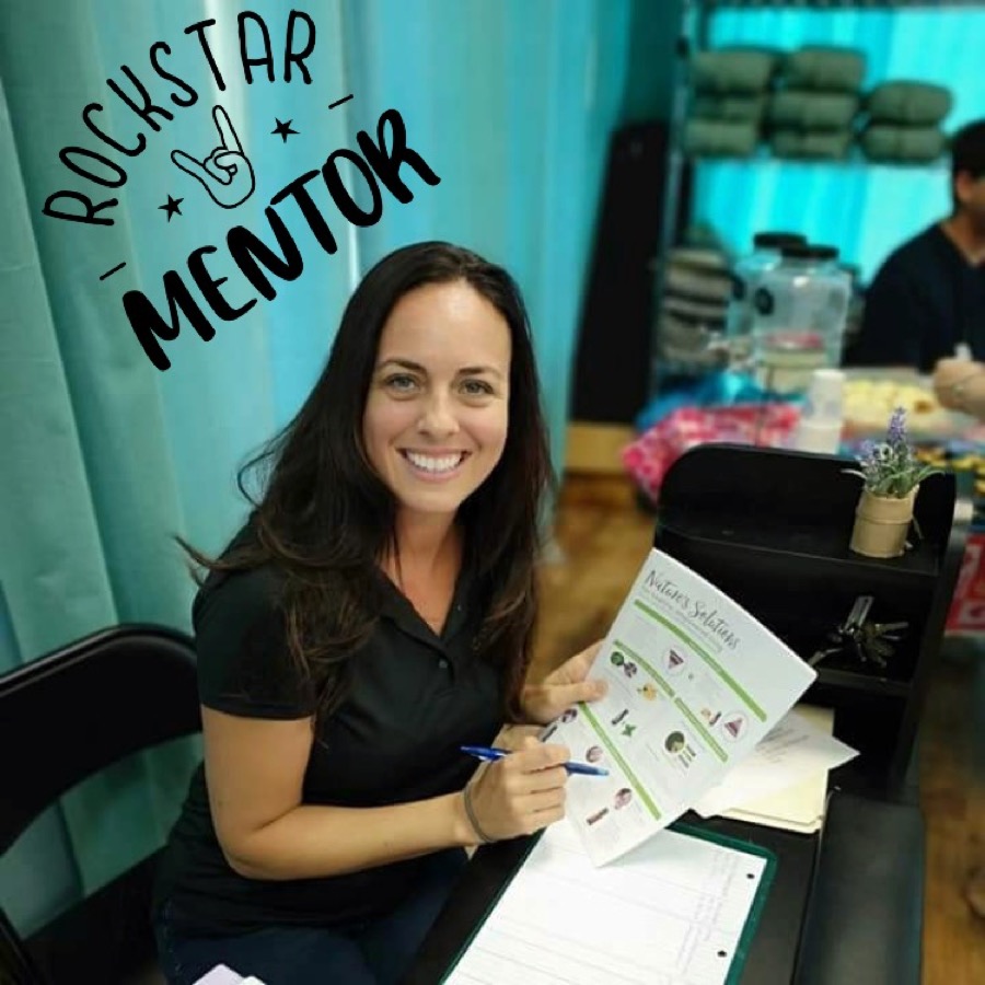 Polished mentor-style event image showing a woman smiling across a table with a worksheet and pen.